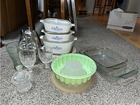 Full lot as arranged on carpet showing Corningware dishes stacked, glassware, plastic Jell-O mold, glass baking dishes, and blender base