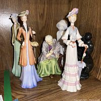 Front view of three ceramic ladies figurines with an elderly grandmother figurine in the background