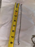 Chain necklace measuring about 8 inches with small cherry pendant next to a yellow tape measure for scale.