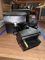 Polaroid OneStep 600 camera with black carrying case on wooden surface