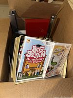 Box containing Wii video games Big Brain Academy and Game Party 3 along with controllers and a flashlight.
