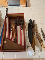 Wide view of boxed Cutco knives with wooden handles and brass rivets, showing knives and display box on kitchen counter