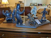 Full view of the entire set of seven Inuit soapstone figures arranged on a display base with inscriptions and artist signature.