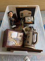 Overall view of the lot in a plastic bin showing various items including a wooden box, beer stein, and Martin Luther bobblehead