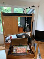 Photo showing a wide view of desk area with wooden shelving, Fifine microphone, postal scale at lower left, wooden desk organizer containing various office supplies, rack of CDs or DVDs, and small monitor on right.