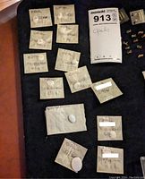 Assortment of glassine packets containing oval white opal cabochons labeled with approximate weights