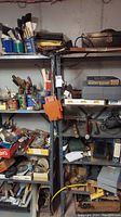 Shelving unit with assorted hardware, tools, clamps, and containers in a basement surrounding.