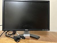 Front view of Dell monitor showing screen, bezel, Dell logo, base stand, and cables.