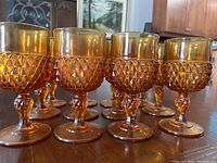Front view of 12 vintage-style golden amber wine glasses with diamond-cut pattern on bowl and stem.