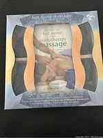 Closed kit box showing the front graphic of the hot stone massage book and kit containing 12 stones.