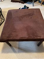 Top view of square seat or coffee table with dark brown faux suede cover showing surface condition.