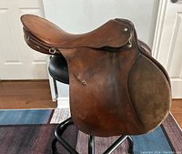 Side profile of the vintage brown leather saddle showing texture and metal fittings.