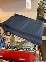 Stack of two canvas bags, a blue one on top and a beige one below, folded and placed on a tiled counter