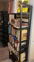 Full front view of black wooden folding bookshelf filled with multiple books on all shelves.
