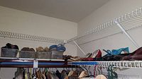 Wide view of shelves loaded with various women's shoes and slippers, some stored in clear plastic bins.