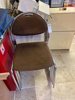 Stack of six brown fabric office side chairs with chrome frames, showing the stacking feature and overall condition.