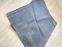 Photo of one black desk chair mat with geometric cityscape outline in light gray, showing some dust and creasing.