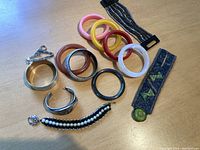Top view of the plastic bangles, metal and beaded bracelets, and fabric bracelet spread out on a wooden surface.