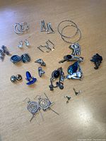 Full assortment of costume jewelry including multiple pairs of earrings and several pins arranged on a wooden surface.