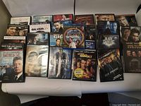 Wide view of 22 DVD cases laid out on table, showing mixed movie titles and genres.