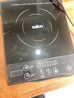 Top view of Salton induction hot plate showing cooking zone, control panel, and brand logo.