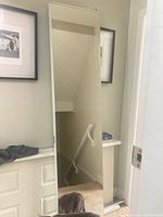 Full view of the mirror bifold door mounted, showing reflective surface and white frame.