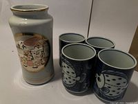 Ceramic pot and five cups displayed showing artwork and fish design.