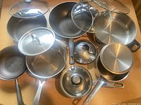 Full set of pots, pans, lids, and steamer insert displayed to show variety and condition.