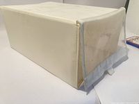 Side view of used Ikea fabric shoe container with clear plastic front window and pull tab. Shows fabric dirt marks.