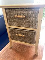 Front view showing full cabinet with two wicker basket drawers and wooden handles.