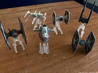 Six Star Wars model ships arranged on a wooden surface, showing five ships mounted on clear plastic stands and one free standing.