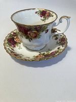 Tea cup placed on matching saucer showing floral pattern and gold trim.