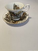 Photo of a vintage Royal Albert teacup featuring scenic British cottages with gold trim, posed with matching saucer