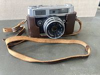 Front view of Mamaya Ruby camera with lens and leather strap holder, showing camera and strap condition.