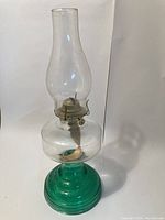 Full view of vintage oil lamp with green glass base and tall clear glass chimney