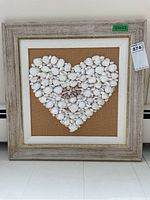 Full view of the framed seashell heart artwork showing wooden frame, fabric backing, and shell arrangement