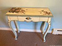 Front view of the hand painted hall table showing the curved legs, drawer with cup pull handle, and painted bird and butterfly design on top.