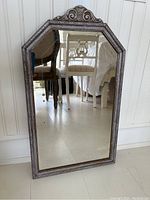 Full view of vintage octagonal wooden framed mirror showing reflective surface and ornate carved wood top piece