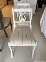 Pair of vintage style white chairs with harp back design and striped upholstered seats seen from above and front.