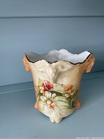 Front view of the Nippon style plant pot showing floral decoration and ornamental handle shaped as a face.