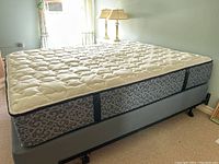Overall view of mattress, box spring and metal frame assembled in room