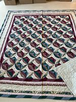 Full view of the quilt laid flat showing the repeating floral petal pattern and multi-border design.