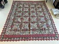 Full view of the handmade quilt spread on floor showing full pattern and scalloped edges.