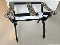 Front view showing black wood folding frame and fabric straps with floral pattern.