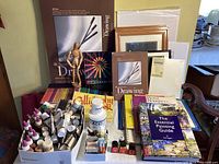 Photo showing assortment of paints, bottles, drawing tools, books, calligraphy ink, and drawing mannequins arranged on a table.