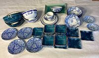 Full view of all plates, bowls, and small dishes showing blue and white porcelain pieces and turquoise ceramic dishes on white background.