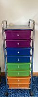 Front view of the tall rolling organizer showing all colorful drawers and tarnished top surface