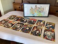 View of 12 Japanese ukiyo-e style paper prints and one framed silk painting on display on table