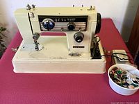 Vintage off-white Morse sewing machine on a pink surface, with foot pedal attached and power cord visible