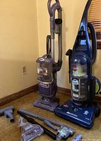 Two upright vacuum cleaners: Shark Navigator Lift-Away and Bissell Rewind PowerClean with accessories on carpeted floor.